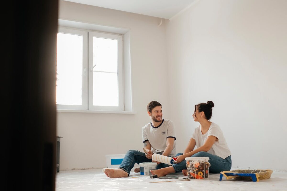 A joyful couple sitting on the floor, painting their new apartment and enjoying each other's company.