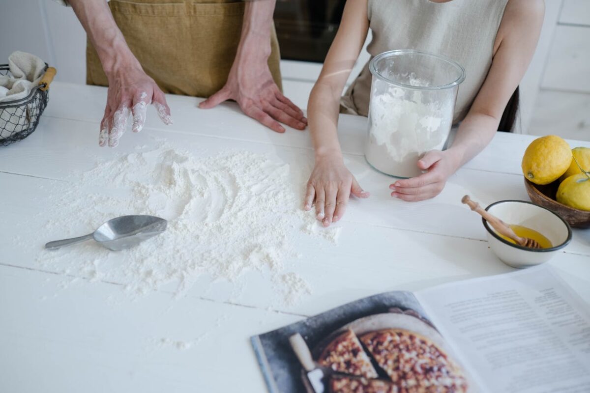 A father and daughter engage in baking, surrounded by flour, lemons, and ingredients, creating a warm family moment.